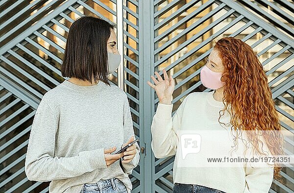 Vorderansicht Freundinnen mit Gesichtsmasken im Freien im Gespräch