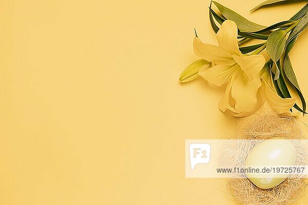 Erhöhte Ansicht frische Lilie Blume mit Osterei Nest gelben Hintergrund
