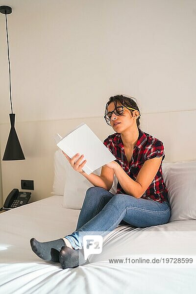 Attraktive junge Frau liest ein Buch im Hotelzimmer
