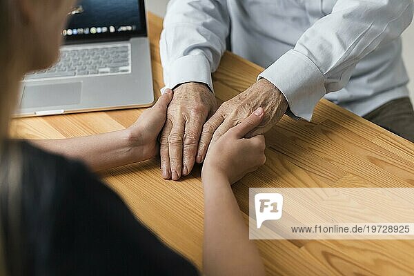 Krankenschwester hält Hände eines älteren Mannes Erleichterung