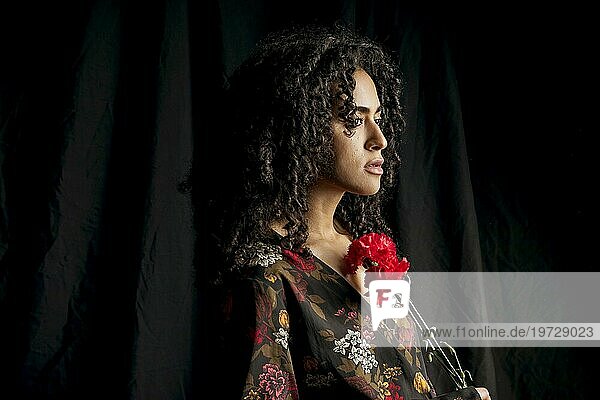 Attraktive ethnische Frau mit roten Blumen dunkel