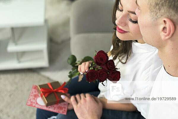 Mann umarmt Frau mit roter Blumenliege