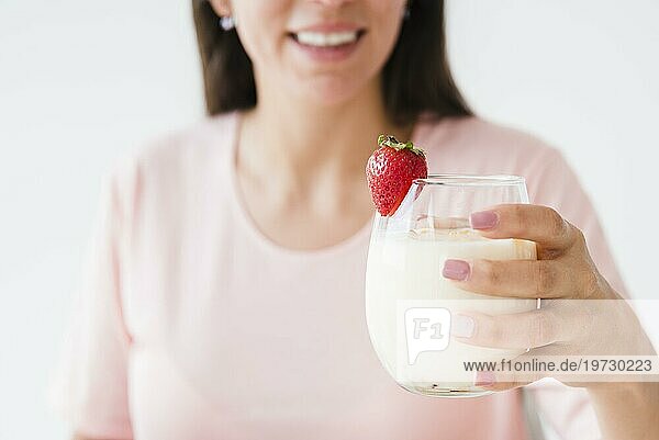 Close up lächelnde junge Frau hält Joghurt Glas mit Erdbeere