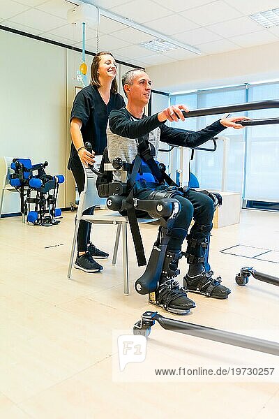 Mechanisches Exoskelett. Weibliche Physiotherapie Arzthelferin hebt behinderte Person mit Roboterskelett zum Aufstehen. Futuristische Rehabilitation  Physiotherapie in einem modernen Krankenhaus