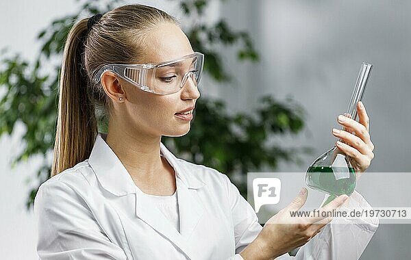 Seitenansicht einer Forscherin mit Reagenzglas Schutzbrille
