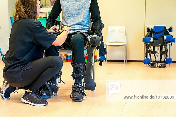 Mechanisches Exoskelett. Physiotherapie in einem modernen Krankenhaus: Eine Physiotherapeutin hilft einer behinderten Person mit einem Roboterskelett mit Bändern. Futuristische Rehabilitation