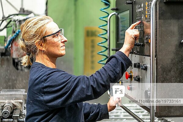 Weibliche Fabrikarbeiterin bei der Arbeit im Bereich der numerischen Steuerung  berührt die Schalttafel  Industriefabrik