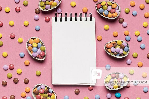 Blanko Spirale Notizblock mit bunten Edelstein Süßigkeiten rosa Hintergrund umgeben