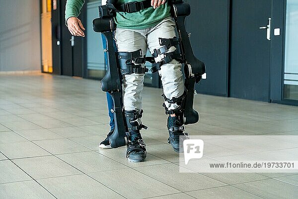 Mechanisches Exoskelett  Physiotherapeut  der mit einer nicht wiederzuerkennenden behinderten Person mit Roboterskelett geht  Physiotherapie in einem modernen Krankenhaus: