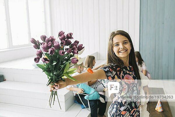 Fröhliches Mädchen zeigt Blumenstrauß Geburtstagsfeier