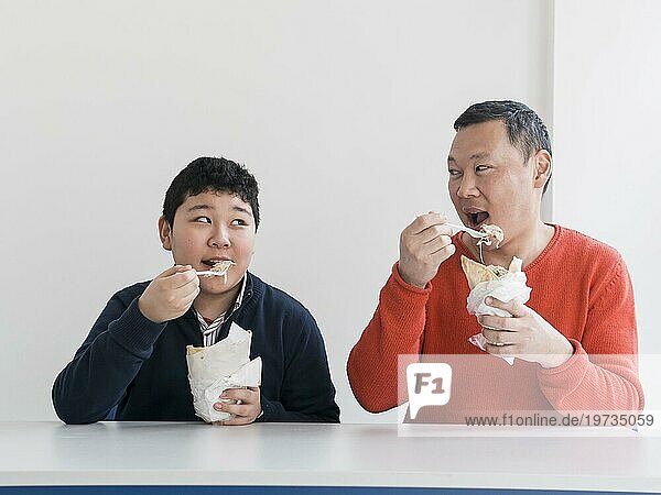 Asiatischer Vater und Sohn essen Fast Food