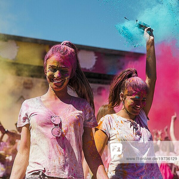 Zwei junge Frauen bedeckt mit Holi Farbe tanzen Holi Festival