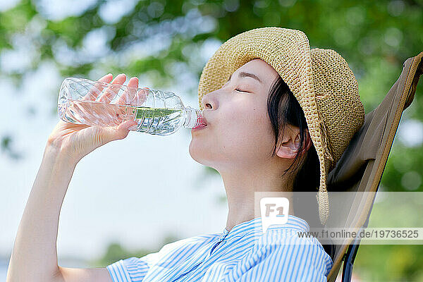 Young Japanese woman drinking water outside