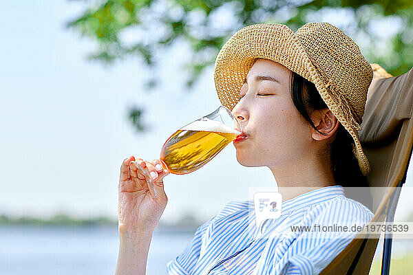 Young Japanese woman enjoying a cold beer outside