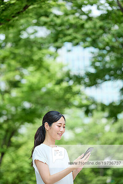 Japanese woman using smartphone in a city park