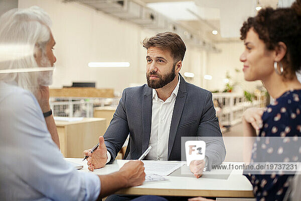 Male lawyer discussing over contract with adult couple