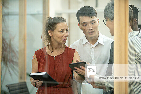 Businesswoman discussing over digital tablet with coworkers