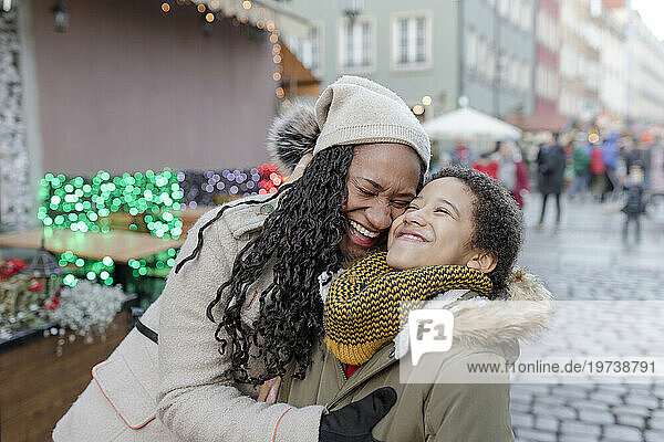 Cheerful mother hugging son at Christmas market
