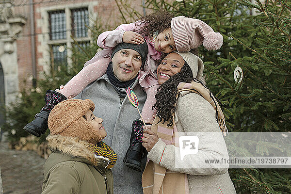 Happy family embracing and having fun together near Christmas tree