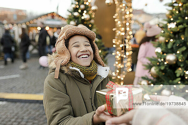 Hands of woman giving gift to boy at Christmas market