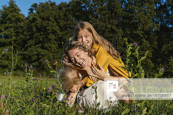 Happy mother enjoying with daughters in flower field
