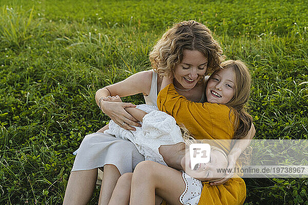 Happy mother enjoying with daughters on grass