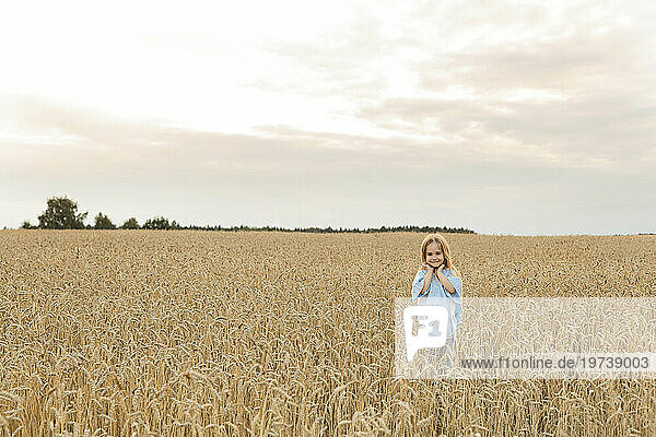 Smiling girl standing amidst field under sky