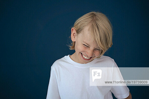 Cheerful boy laughing against blue background