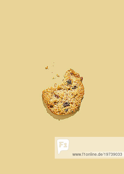 Raisin cookie with missing bite against yellow background
