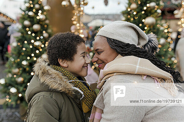Smiling mother rubbing noses with son at Christmas market
