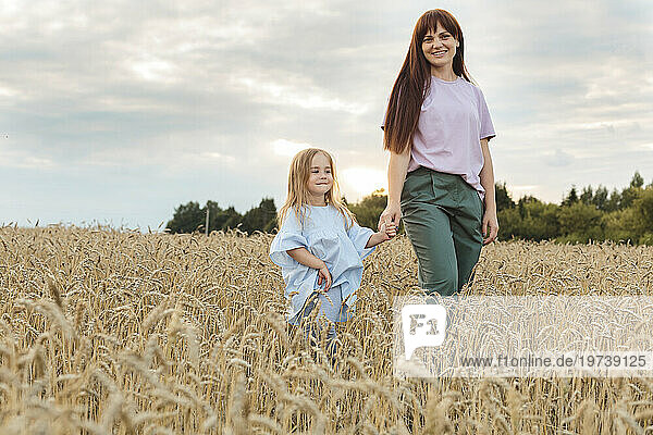 Smiling mother with daughter walking amidst field
