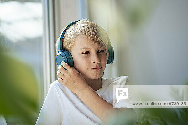 Boy wearing wireless headphones listening to music at home