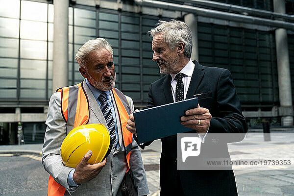 Businessman discussing with colleague over tablet PC on road
