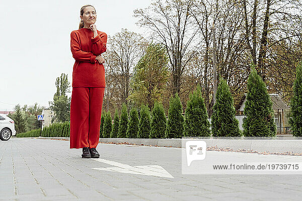Woman with hand on chin standing near arrow sign at street