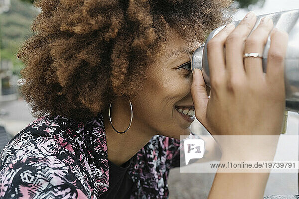 Happy young woman looking through coin operated binoculars