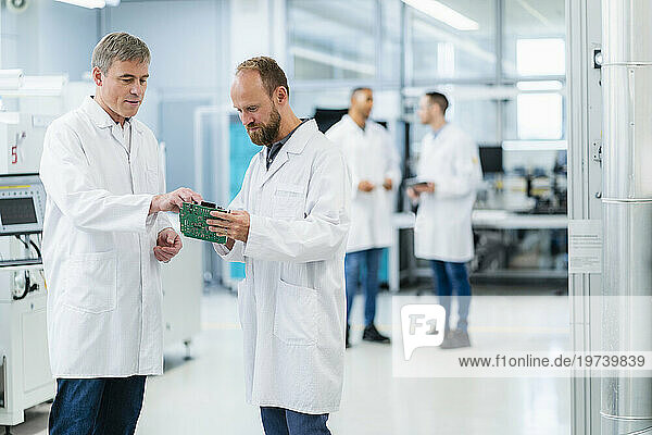 Electrical technicians checking motherboard in electronics factory