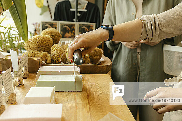 Saleswoman cutting homemade soap on table in shop