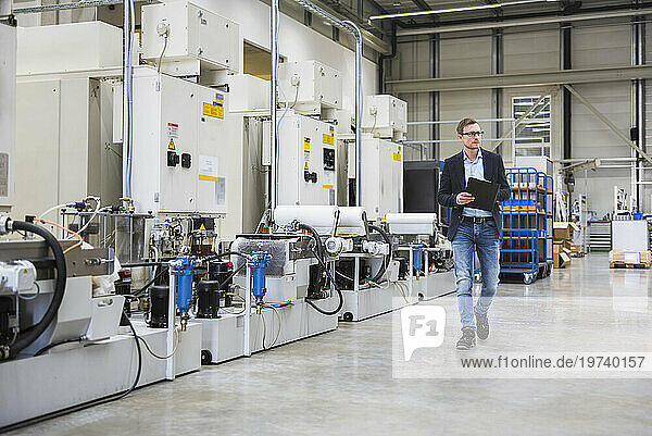 Engineer holding file folder and walking in factory