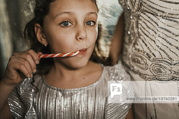 Girl eating candy cane with mother at home