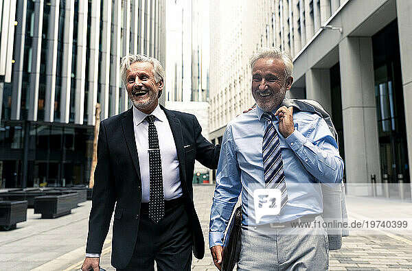 Happy senior businessmen walking with each other on road