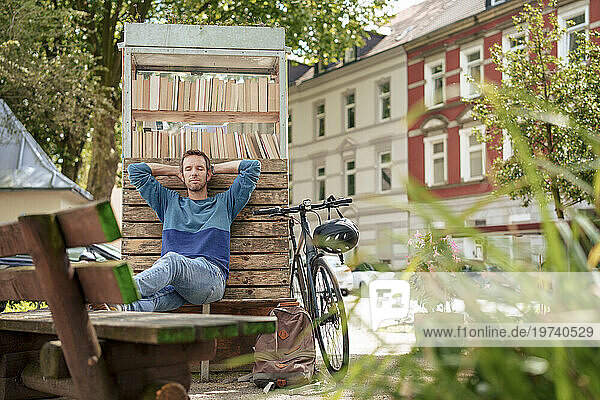 Mature man relaxing and leaning on bookstand