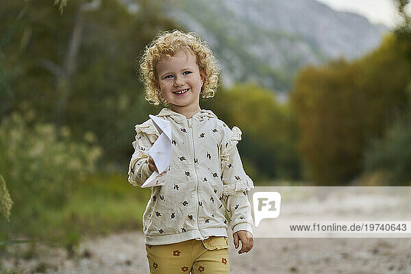 Happy curly haired girl holding paper boat