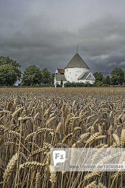 Denmark  Bornholm  Nylars  Storm clouds over field in front of Nylars Church