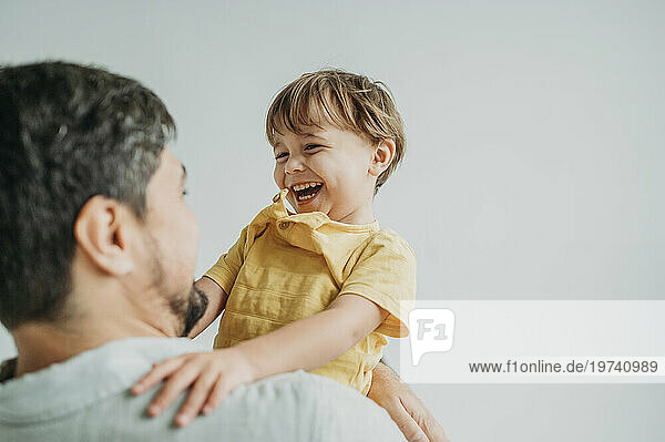 Happy man enjoying with son against white background
