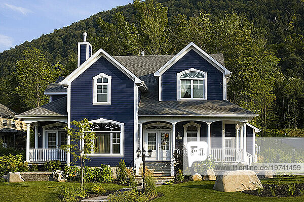 Large single family home with blue facade  white trimmed windows and a landscaped front yard; Quebec  Canada