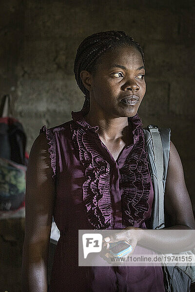 Haitian woman stands holding her cell phone; Port-de-Paix  Haiti