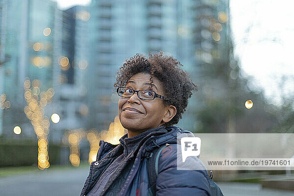 Close-up portrait of a woman standing outdoors in Vancouver at twilight  smiling and looking upward; Vancouver  British Columbia  Canada