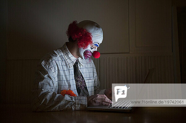Clown wearing a shirt and tie uses a laptop computer and smart phone simultaneously; Lincoln  Nebraska  United States of America