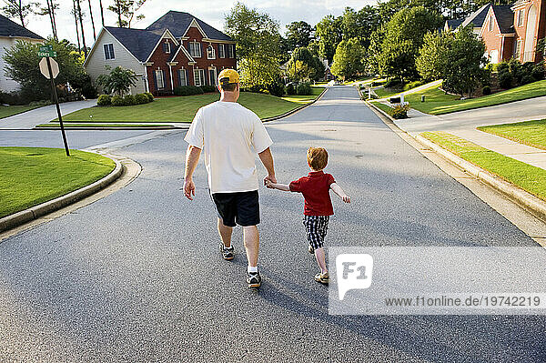 Father and son hold hands while walking through their neighborhood; Marietta  Georgia  United States of America