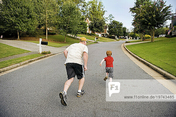 Father races his son down a street in their neighborhood; Marietta  Georgia  United States of America